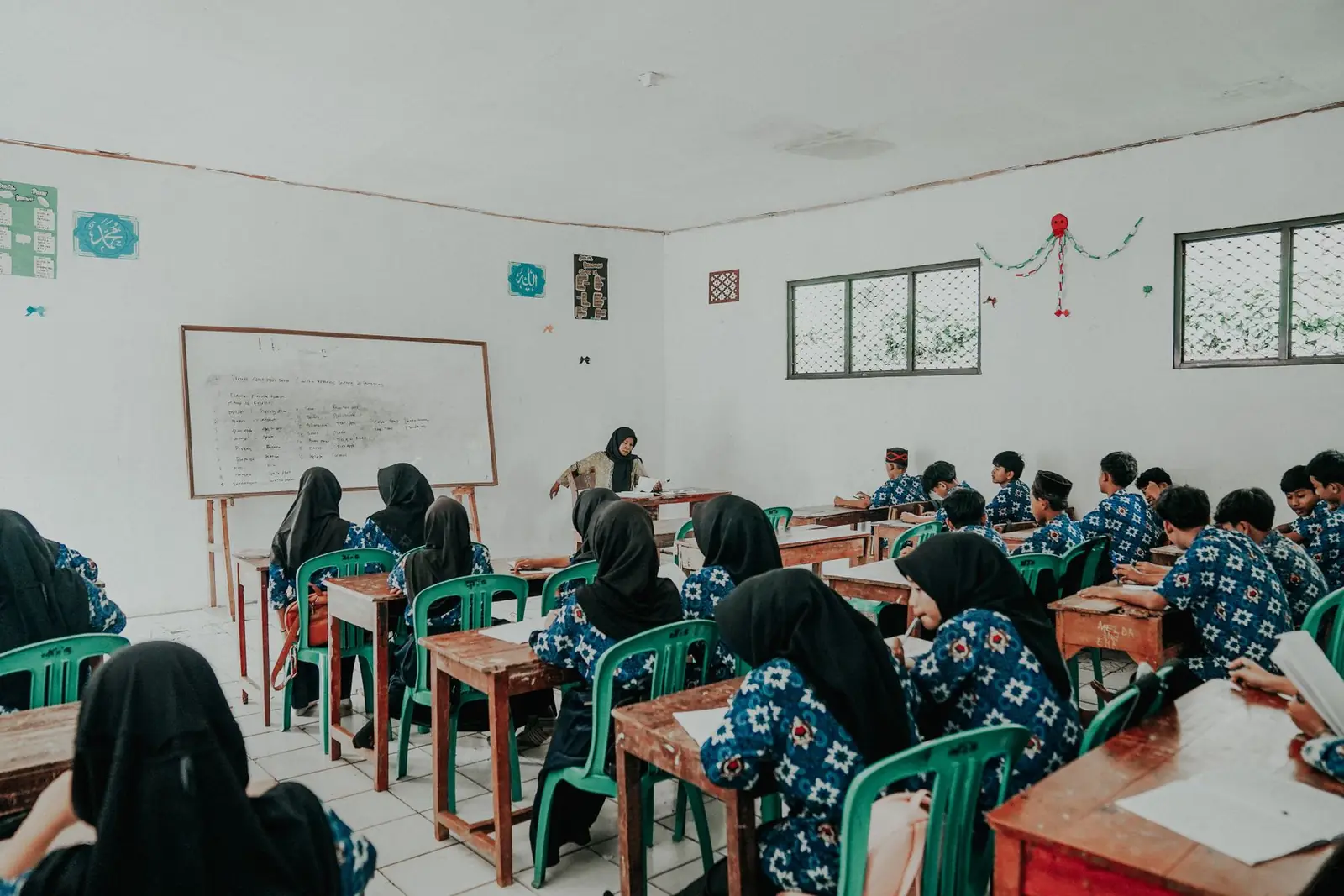 Ruang kelas dengan siswa berseragam batik yang sedang belajar bersama guru
