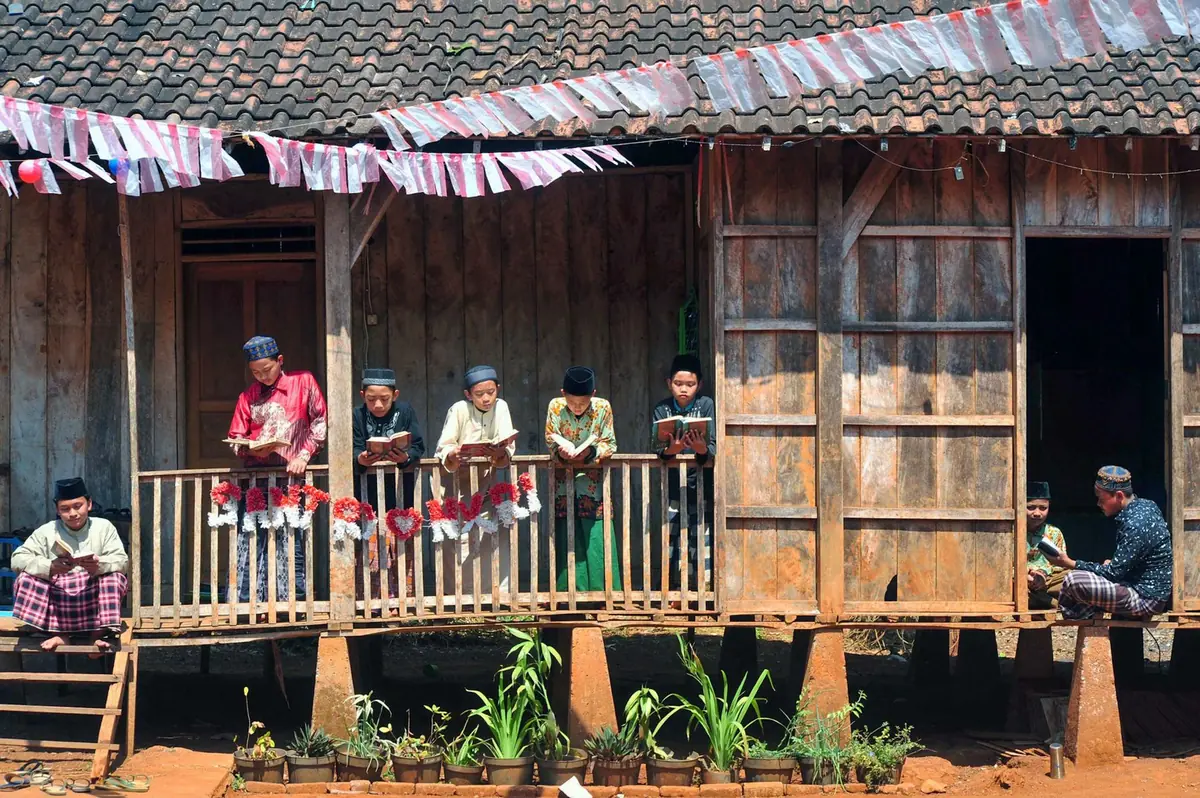 Anak-anak membaca bersama di teras rumah kayu tradisional